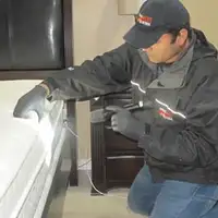 Bed bug inspection technician checking a mattress and bed frame for signs of infestation in Omaha, NE