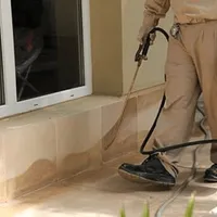 General pest control technician spraying exterior perimeter around a home in Omaha, NE
