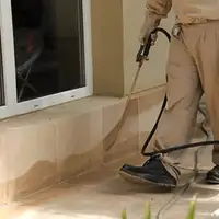 General pest control technician spraying exterior perimeter around a home in Omaha, NE