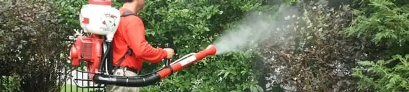 Mosquito control technician fogging shrubs and landscaping for mosquito treatment in Omaha, NE