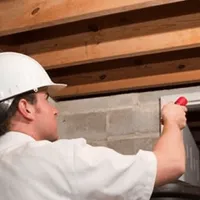 Termite inspection technician checking a basement wall and framing for termite activity in Omaha, NE