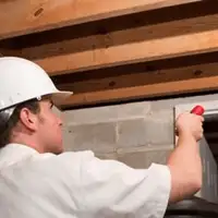 Termite inspection technician checking a basement wall and framing for termite activity in Omaha, NE
